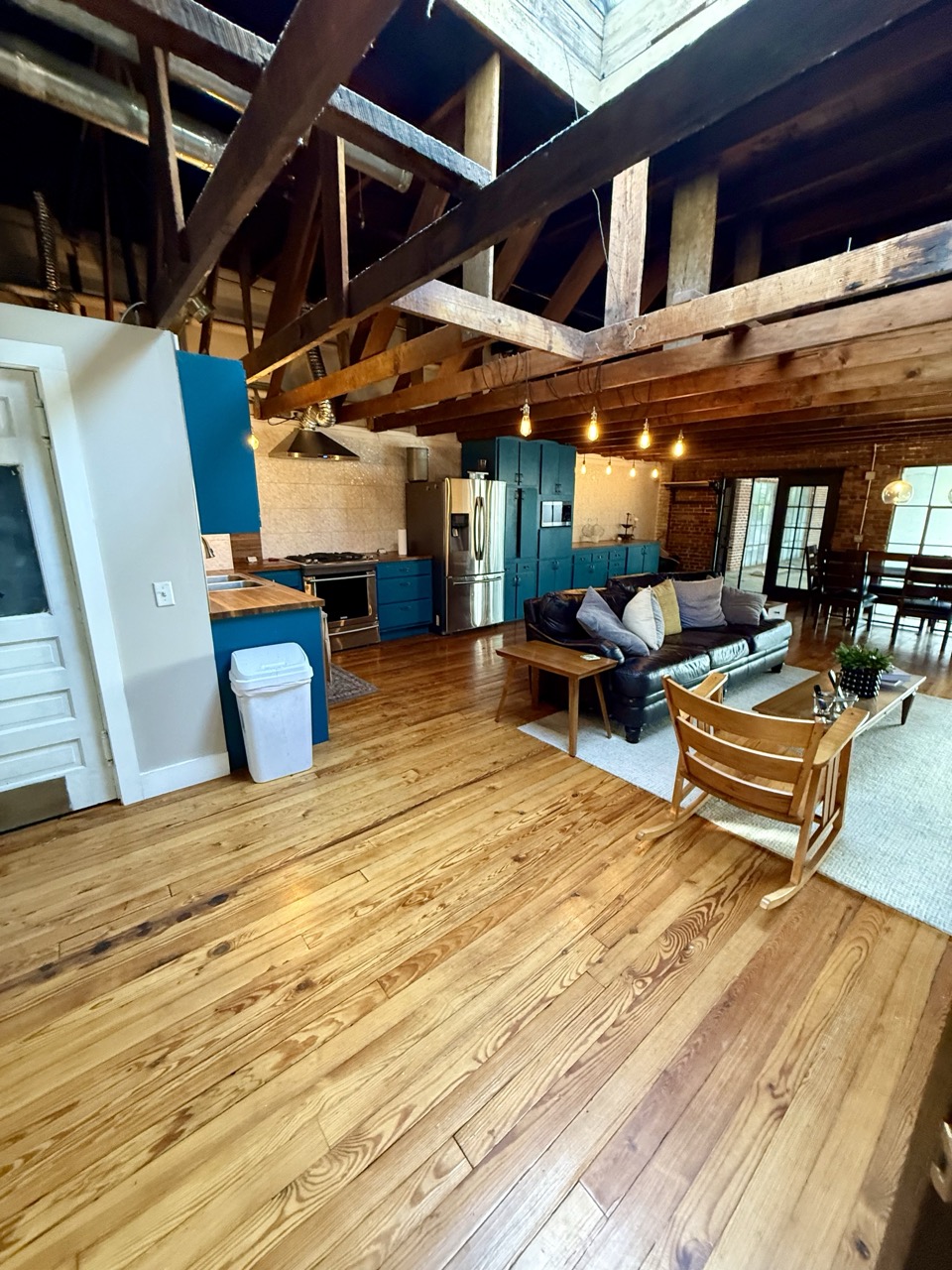 The Hidden Loft's living room under the original timber roof, a skylight overhead and the kitchen beyond.
