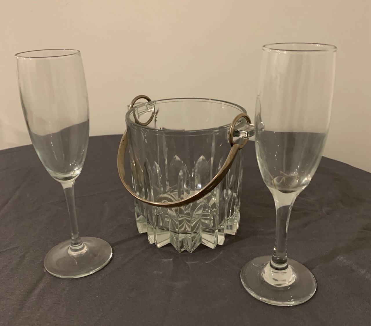 A cut-glass ice bucket with a gold handle, flanked by two champagne flutes.