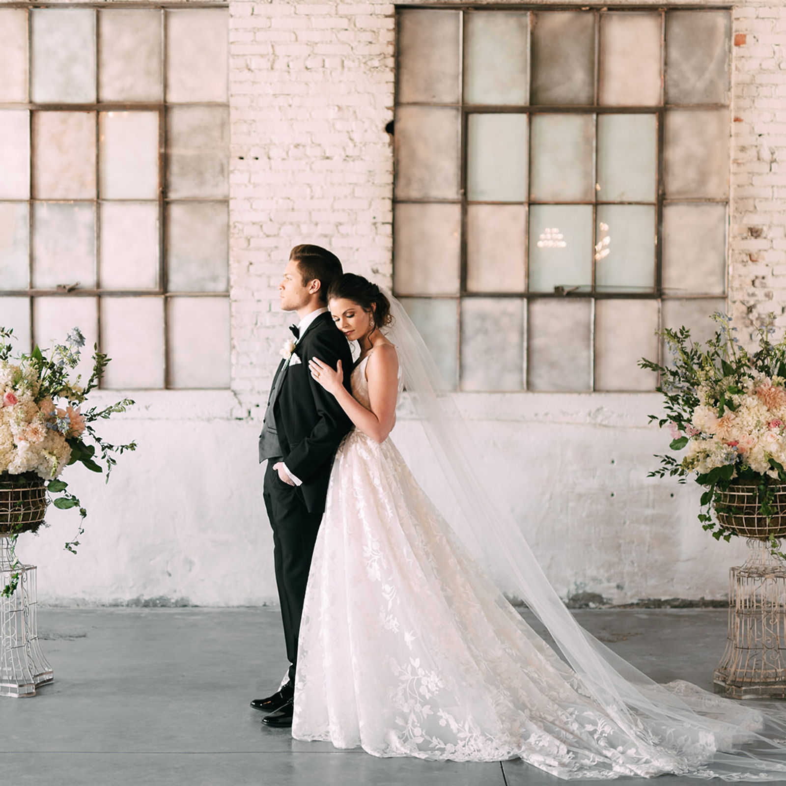 A bride and groom against the ballroom's whitewashed brick and antique steel-frame windows.