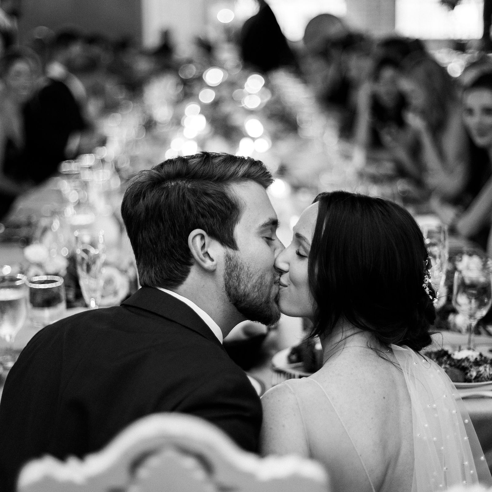 A black-and-white candid kiss during the reception.