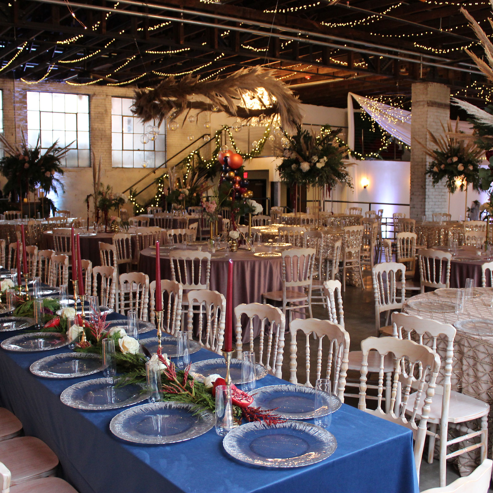 Reception tables in the evening, pampas grass and candlelight against the brick.